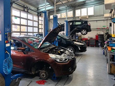 Unutrašnjost radionice Autoservisa Rihtarić: dva vozila na dvostupnim dizalicama, crveni automobil s otvorenom haubom, ormarići s alatom i gume, slika 6 od 6