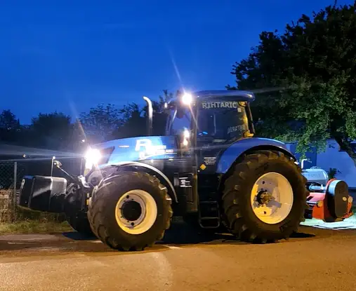 Plavi traktor Rihtarić malčiranje noću s upaljenim svjetlima